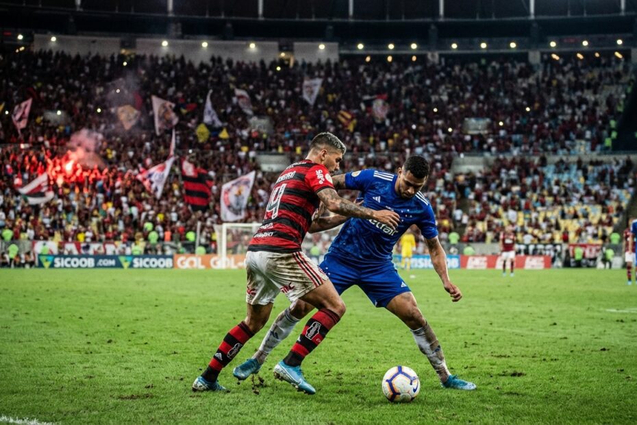 Jogadores de Flamengo e Cruzeiro disputam a bola no estádio do Maracanã sob iluminação noturna
